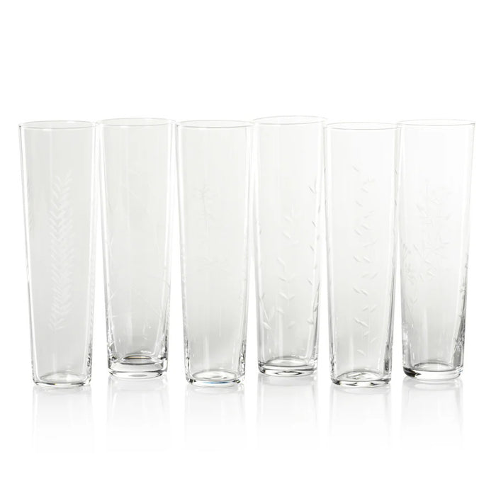 Six FLORA ETCHED CHAMPAGNE FLUTES by ZODAX are lined up in a row. Each clear glass showcases a unique, subtle etched botanical or leaf pattern, beautifully contrasting against a white background.