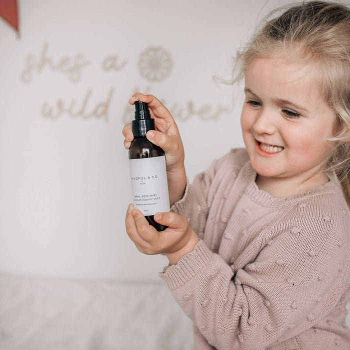 Child holding a bottle of 'Naturals' product with a blurred background