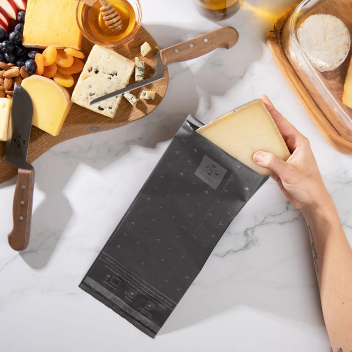 A box of FORMATICUM - REUSABLE CHEESE STORAGE BAGS by FORMATICUM features a white and black design, “Reduce cheese waste” and “Keeps cheese fresher, longer” text, and contains 10 reusable bags.