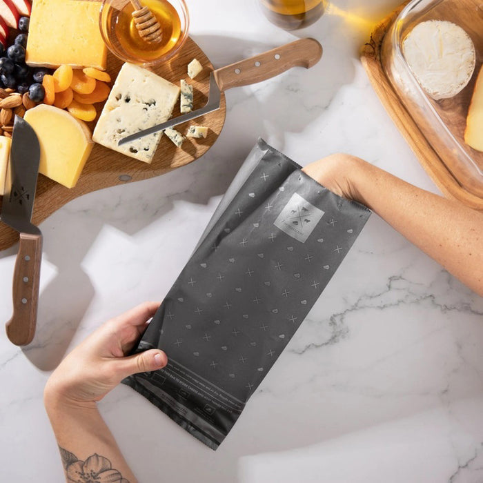 A box of FORMATICUM - REUSABLE CHEESE STORAGE BAGS by FORMATICUM features a white and black design, “Reduce cheese waste” and “Keeps cheese fresher, longer” text, and contains 10 reusable bags.