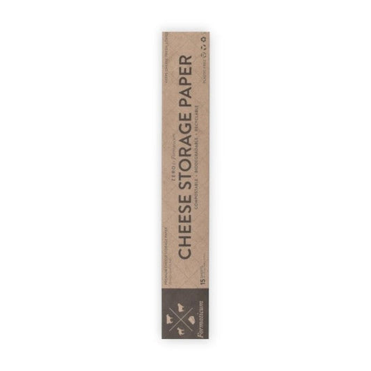 A hand holds a sheet of FORMATICUM - ZERO CHEESE STORAGE PAPER with green illustrations, next to a brown FORMATICUM box. The partially unrolled cheese storage paper is ideal for keeping cheese fresh at home.