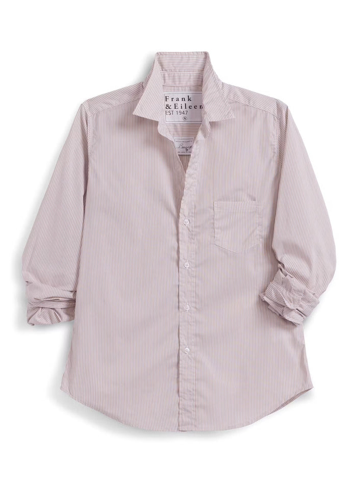 Wearing the FRANK & EILEEN EILEEN Relaxed Button Up in Italian Cotton Tan Stripe and a pair of jeans, a woman strolls down a sunny, café-lined street, smiling as she passes by tables and people. The shirt’s flattering bust button placement adds an elegant touch to her effortless style.