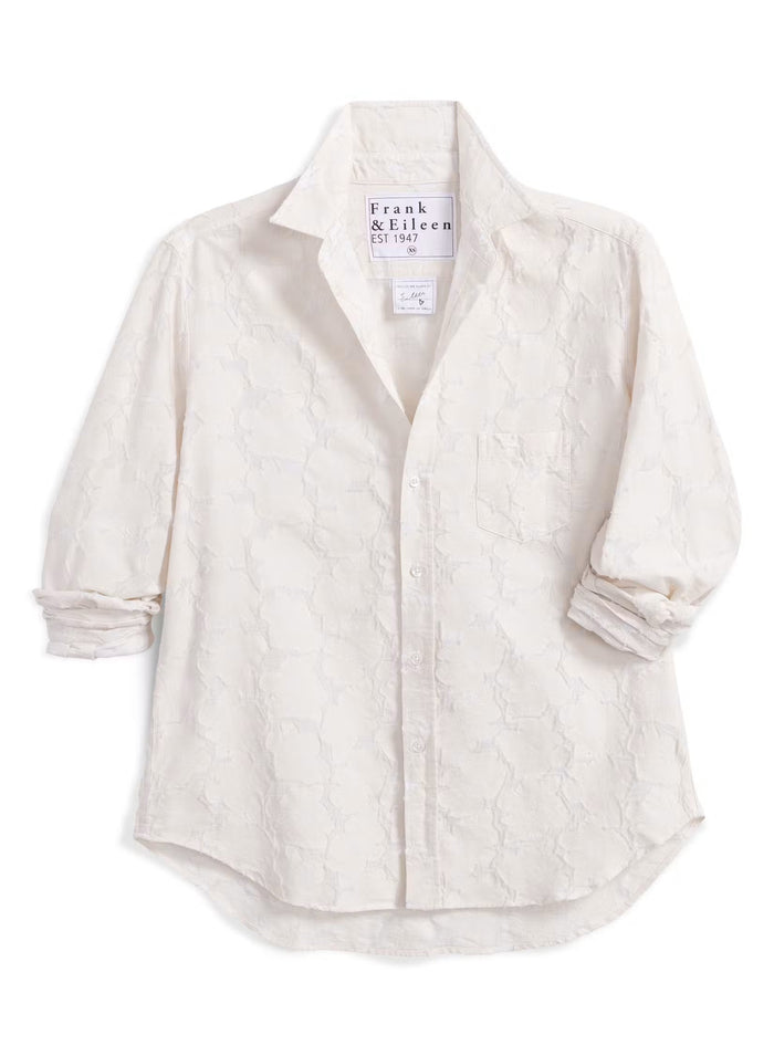 Introducing the FRANK & EILEEN - EILEEN Relaxed Button Up in Italian Cotton Textured Natural Flowers: a long-sleeve, button-up white shirt with a subtle floral texture, rolled cuffs, and a pointed collar. Designed for a relaxed fit, this shirt is crafted from premium Italian cotton and features thoughtfully placed buttons to flatter the bust for an effortlessly stylish silhouette. The signature label inside reads “FRANK & EILEEN EST 1947.”.