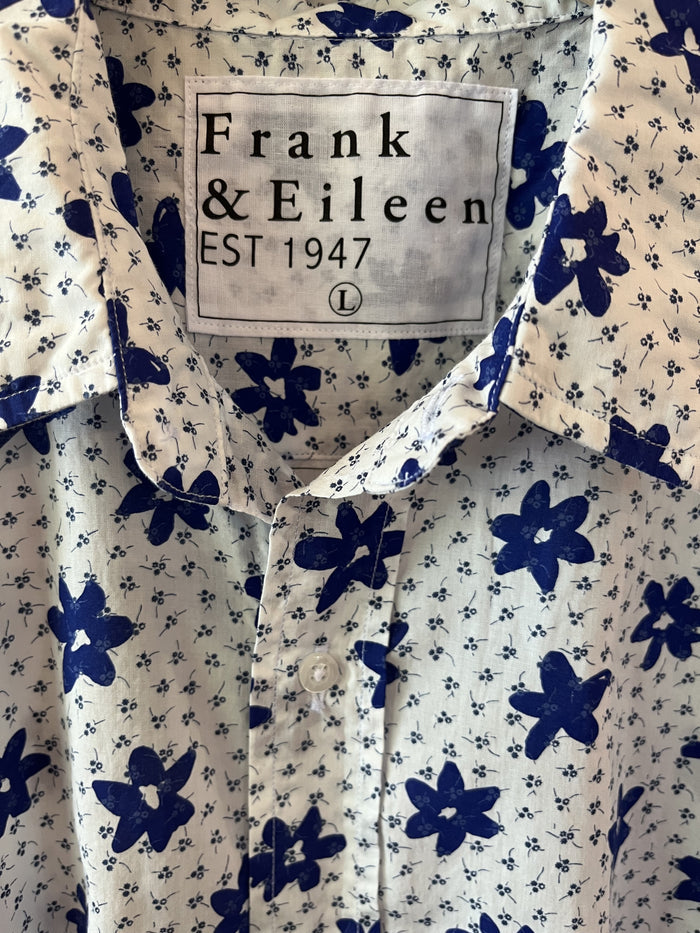 A man with short gray hair and a beard wears the FRANK & EILEEN Finbar Men's Button Up Shirt in Blue and White Small Flowers Big Flowers. He pairs it with dark jeans, standing against a plain white background for an everyday look.