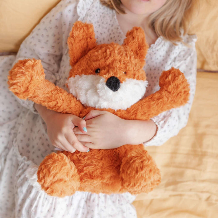Frankl The Weighted Fox teddy being hugged by a child in cozy bedding.