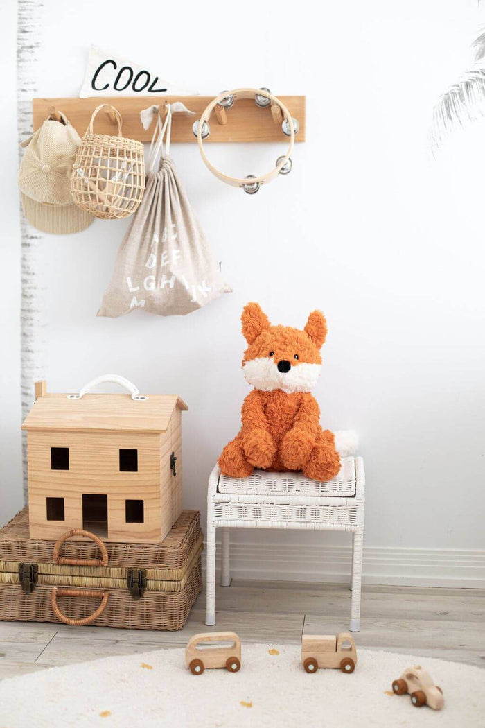 Frankl The Weighted Fox teddy sitting on a white stool in a cozy children's room with toys and decorative items.
