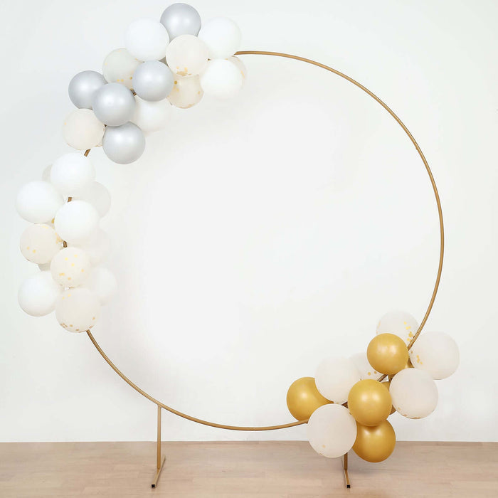 Gold and silver balloon arch with white accents on a plain backdrop