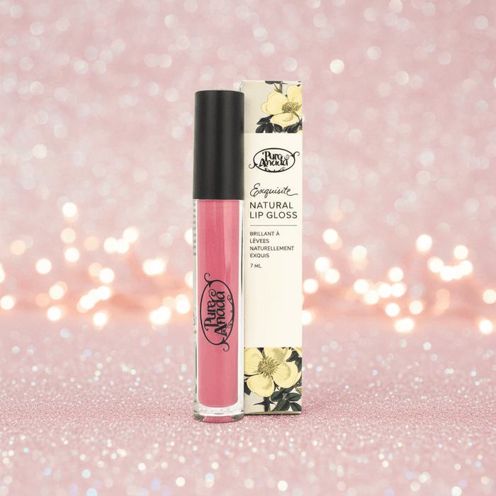 Pink lip gloss with black cap and floral packaging on a glittery pink background