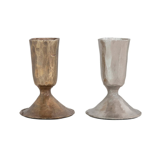 The CREATIVE COOP HAND-FORGED CAST IRON TAPER HOLDERS feature textured surfaces, wide bases, and rustic, handmade appeal in antique brass and silver finishes.