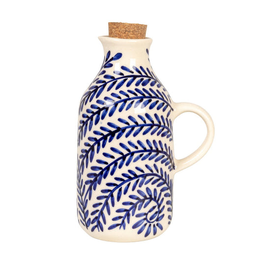 The HAND-PAINTED STONEWARE OIL CRUET WITH CORK STOPPER by CREATIVE COOP features blue leaf patterns and a handle, making it a perfect addition to rustic kitchen decor. Shown on a white background with the cork beside it.