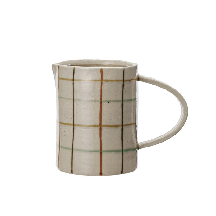 Close-up of the HAND-PAINTED STONEWARE PITCHER by CREATIVE COOP, showcasing an artisanal beige surface with a grid of brown, orange, and light green, plus small dark speckles for added charm.