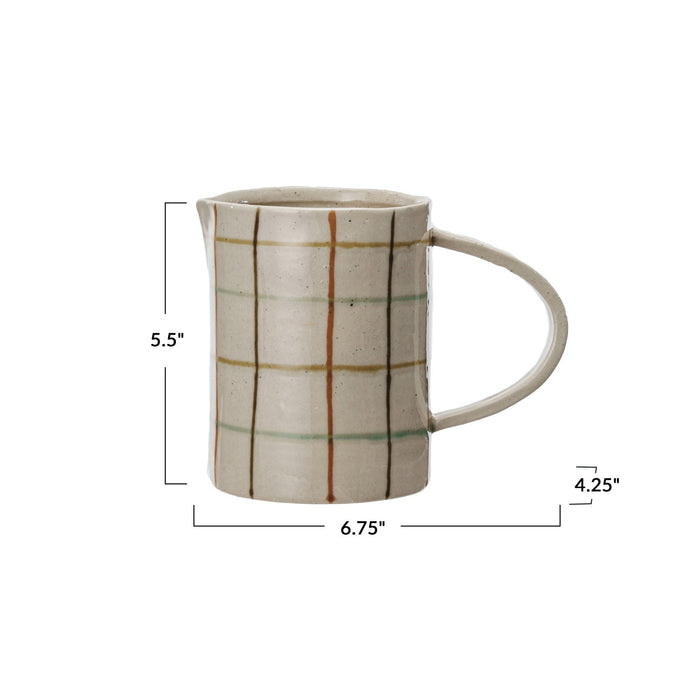 Close-up of the HAND-PAINTED STONEWARE PITCHER by CREATIVE COOP, showcasing an artisanal beige surface with a grid of brown, orange, and light green, plus small dark speckles for added charm.