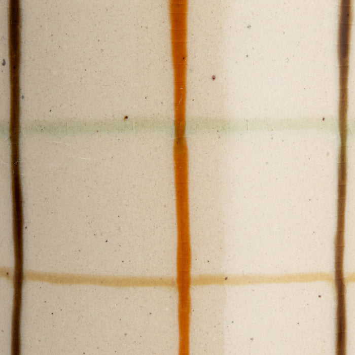 Close-up of the HAND-PAINTED STONEWARE PITCHER by CREATIVE COOP, showcasing an artisanal beige surface with a grid of brown, orange, and light green, plus small dark speckles for added charm.
