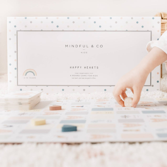 Mindful & Co kids card game packaging with a hand reaching for a card on a wooden surface.