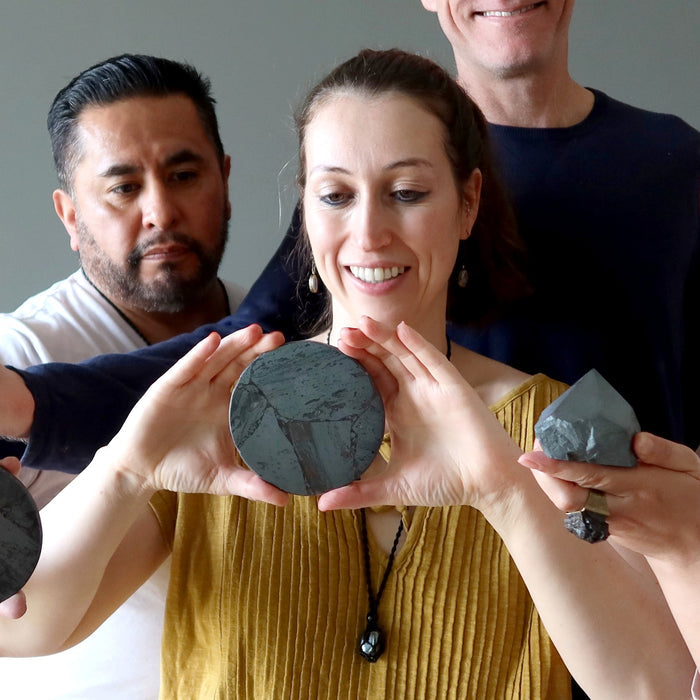 three people holding hematite stones