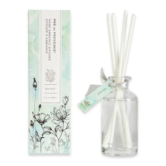 The HERITAGE REED DIFFUSER - SEA SALT by EUROPEAN SOAPS, LLC features white reeds in a glass bottle beside a matching floral box, capturing the elegant, pastel charm of timeless French-inspired products.