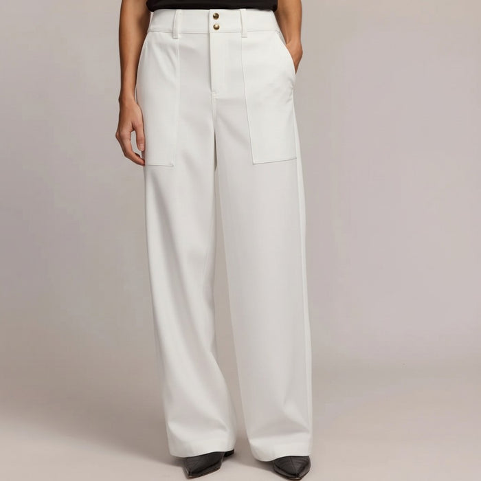 Wearing HINSON WU’s KELLY TRAVELERS TWILL PANT IN WHITE—high-waisted, wide-leg with large front pockets, front seam, and double button closure—paired with black pointed-toe shoes. Torso partially visible against a plain background.