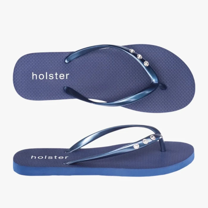 A pair of midnight blue Holster Ladies Holiday Slops, featuring metallic blue straps adorned with sparkling jewels,