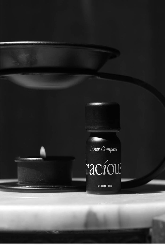 Inner Compass Essential Oil Blend bottle next to a candle, showcasing the grounding essential oil blend for aromatherapy.