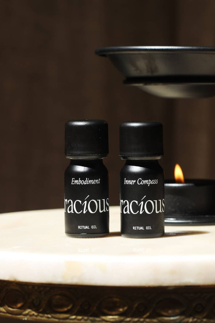 Bottles of Gracious ritual gel: Embodiment and Inner Compass grounding essential oil blend on a marble surface.