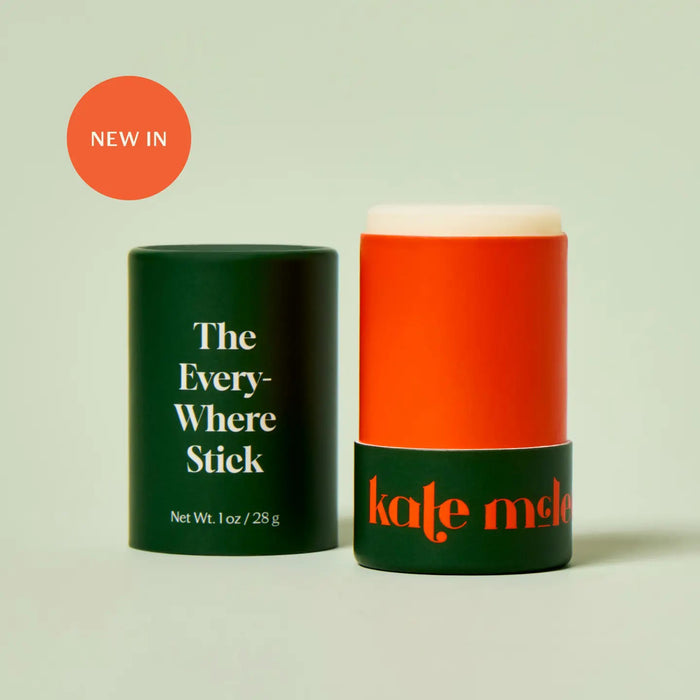 A cylindrical skincare stick features an orange design with "KATE MCLEOD" inscribed. Next to it, a green cap displays "The Everywhere Stick" in white. A red circle above says "New In." Made with pure plant butters, this wax-free formula is a hydration hero, all set against a light green background.