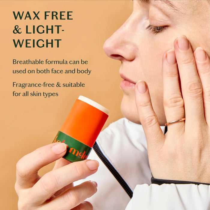 A cylindrical skincare stick features an orange design with "KATE MCLEOD" inscribed. Next to it, a green cap displays "The Everywhere Stick" in white. A red circle above says "New In." Made with pure plant butters, this wax-free formula is a hydration hero, all set against a light green background.