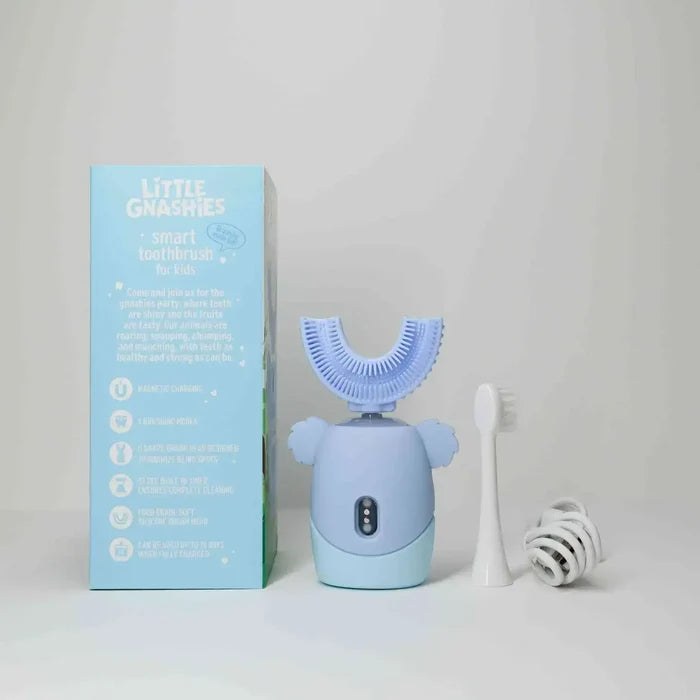 Blue children's toothbrush with packaging and additional brush head on a light gray background