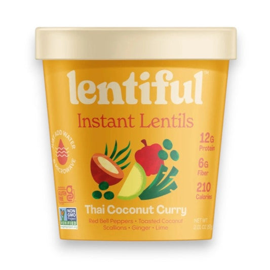 A yellow container of LENTIFUL - THAI COCONUT CURRY LENTILS is surrounded by fresh red bell pepper, lime halves, green onions, coconut flakes, and sliced chili on a green background, highlighting a spicy meal from LENTIFUL.