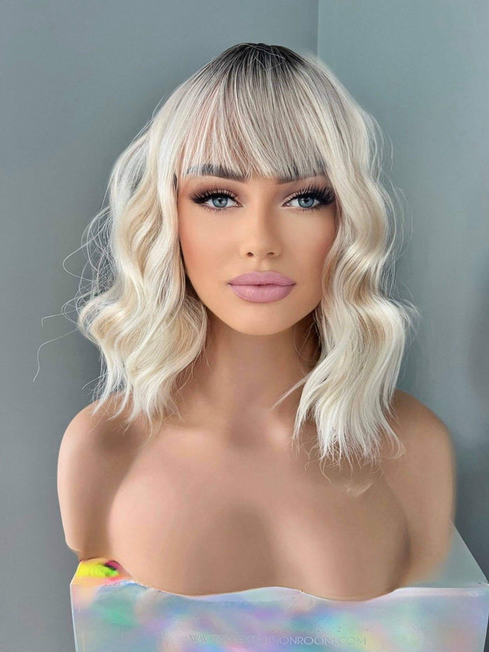 Short white blonde body wave wig with bangs on a mannequin, showcasing effortless style and charm.