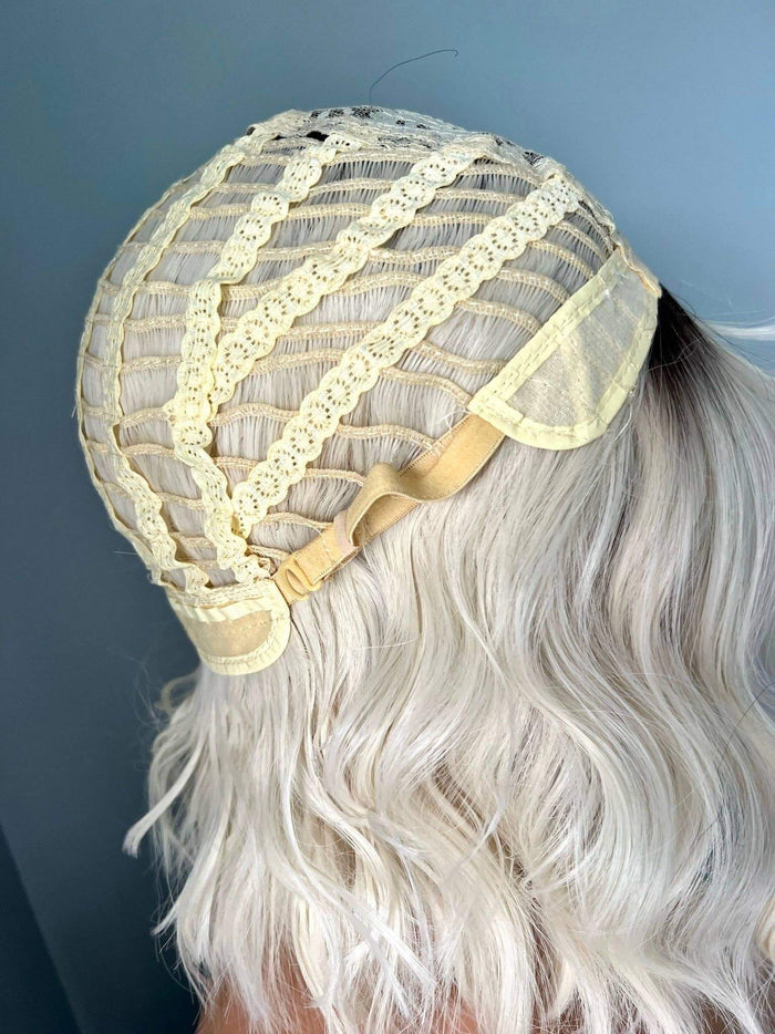 Inside view of a short white blonde wave wig with bangs cap, showcasing the lace front and adjustable straps.