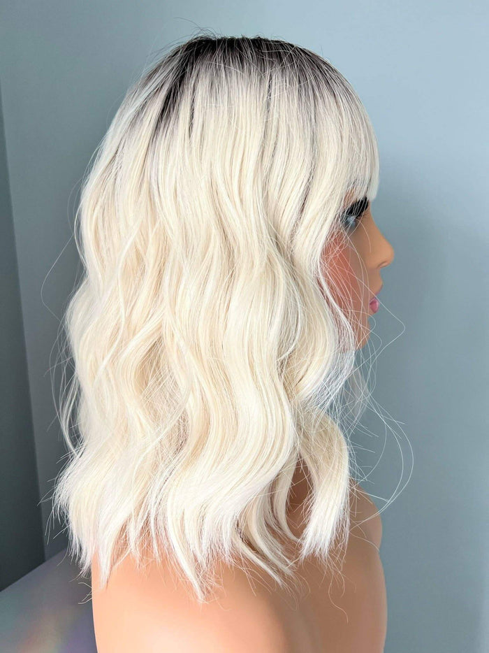 Side view of the Lilah Short White Blonde Body Wave Wig with Bangs, showcasing soft waves and bangs.