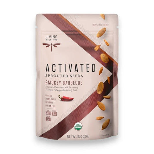 A bag of LIVING INTENTIONS - SMOKEY BARBEQUE SPROUTED SEEDS displays vibrant images of seeds and spices on the front, along with USDA organic, plant-based, and gluten-free labels. This snack from LIVING INTENTIONS features a superfood blend of organic sprouted seeds with a bold smokey barbecue flavor for a wholesome and delicious treat.