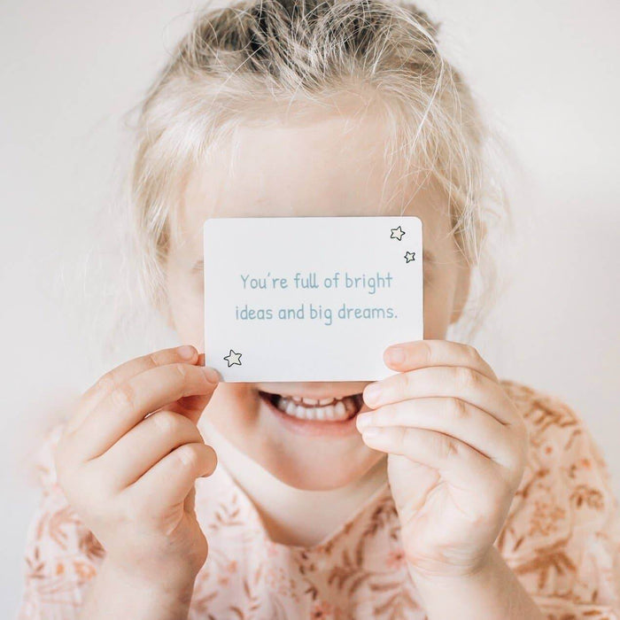 A joyful child holds a Love Notes - Mindful and Co Kids affirmation card promoting bright ideas and big dreams.