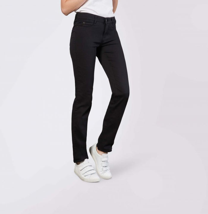 Model wears MAC - DREAM STRAIGHT LEG DENIM by MAC in light blue with a white shirt and white sneakers, standing with one hand in their pocket against a plain light gray background.