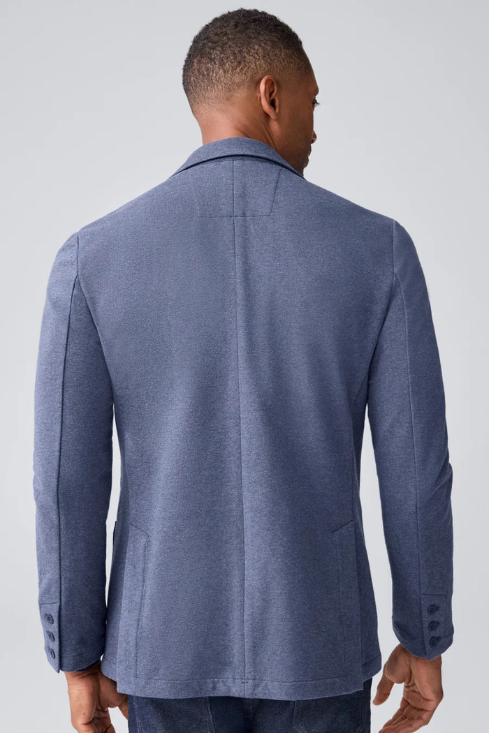 A person in a navy shirt holds open the MACK WELDON ACE BLAZER IN TRUE BLACK, revealing its comfortable, machine-washable design with an inside pocket and inner lining.