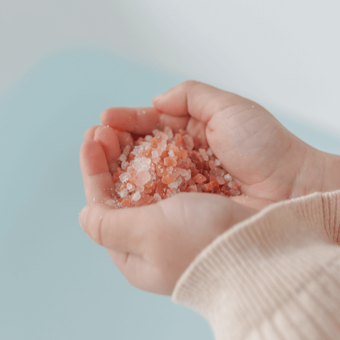 Child's hands holding Magnesium Calming Soak 600g with colorful mineral salts.