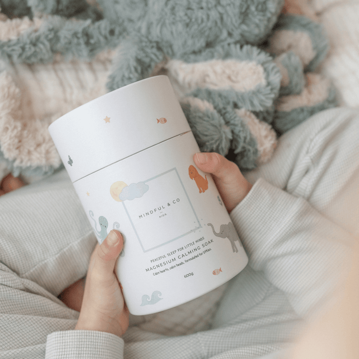 Child holding a container of Magnesium Calming Soak 600g surrounded by a cozy atmosphere.
