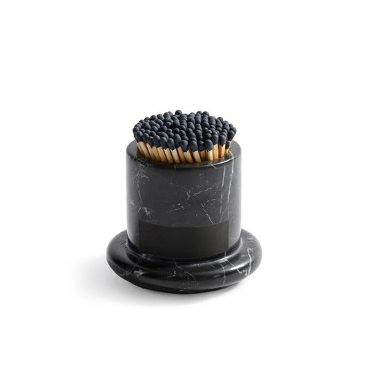 The ZODAX MARBELLA BLACK MARQUINA MARBLE MATCH STRIKE holds black-tip matches upright on a round black marble base, adding a touch of style to your space.