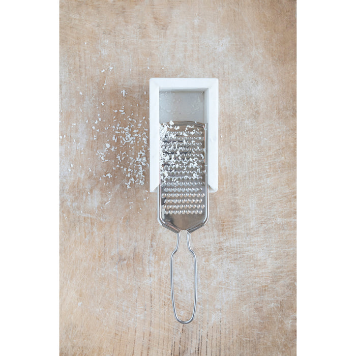 The CREATIVE COOP MARBLE AND STAINLESS STEEL GRATER, with its sleek handle and white marble rest, is shown from above, making it a stylish and modern addition to any kitchen countertop.
