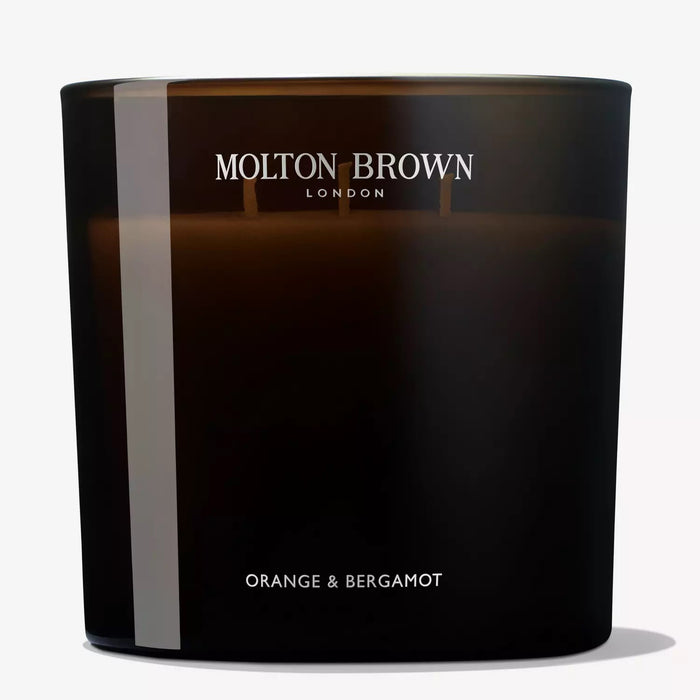 A dark brown MOLTON BROWN ORANGE AND BERGAMOT LUXURY CANDLE 3 WICK releases a refreshing citrus and neroli scent, displayed against a plain light background.