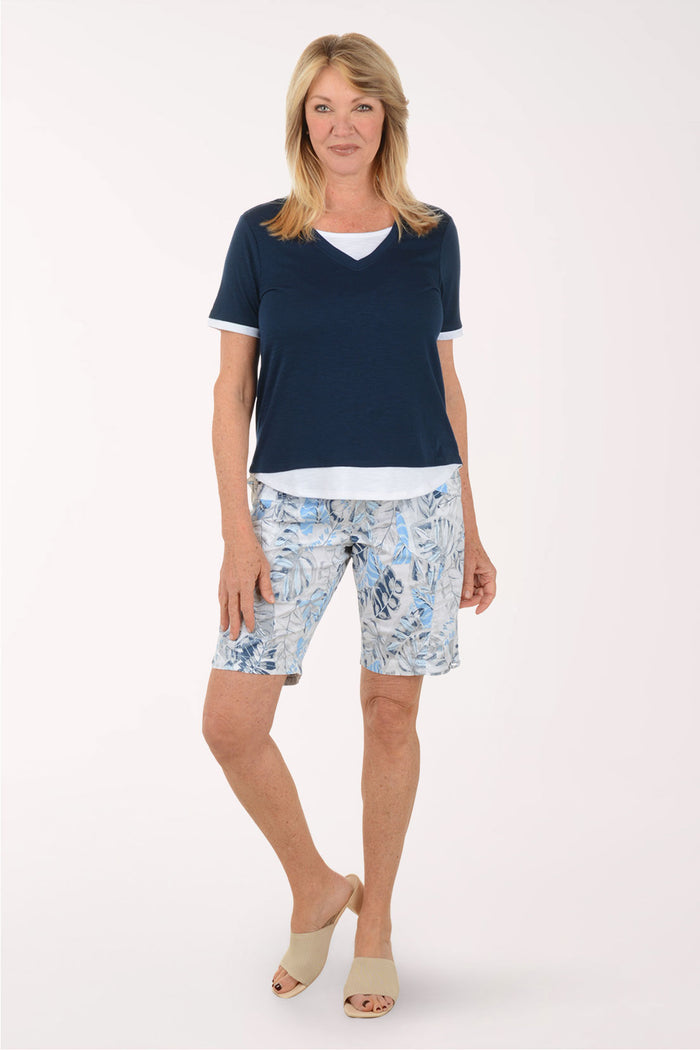 Woman wearing a navy blue top and patterned shorts on a white background