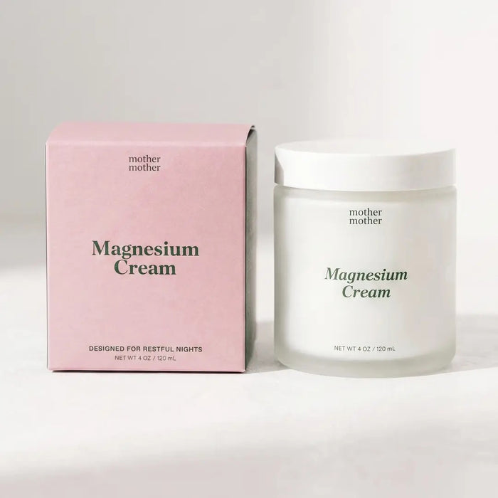 A pink box and a glass jar, both labeled “MOTHER MOTHER - MAGNESIUM CREAM” from the brand MOTHER MOTHER, are arranged side by side on a light surface. The box emphasizes its relaxation support for restful nights, while the unscented magnesium cream in the jar comes with a clean white lid.