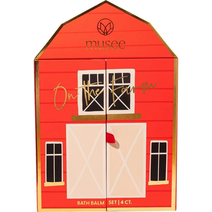 The MUSEE - ON THE FARM BATH BALM SET by MUSEE comes in a charming red, barn-shaped box labeled “musee” that opens to unveil a whimsical farm scene complete with animal figures. The set features four pastel bath balms in blue, yellow, pink, and white—all handcrafted with natural ingredients for a soothing and delightful bath experience.