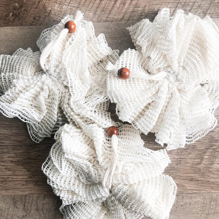 Decorative wreath made of white mesh with wooden beads on a wooden surface