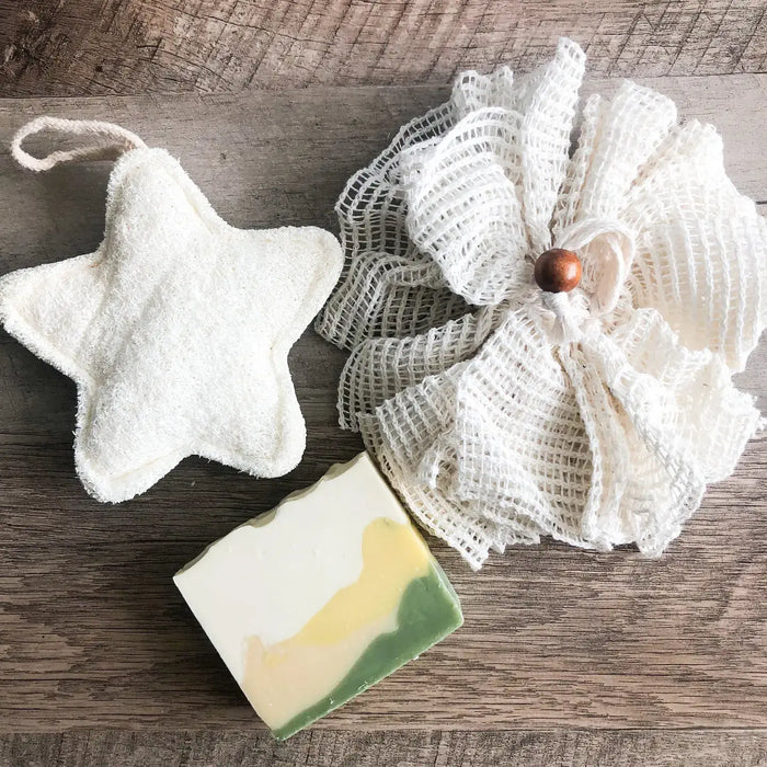 Star-shaped washcloth, mesh scrubber, and bar of soap on a wooden surface