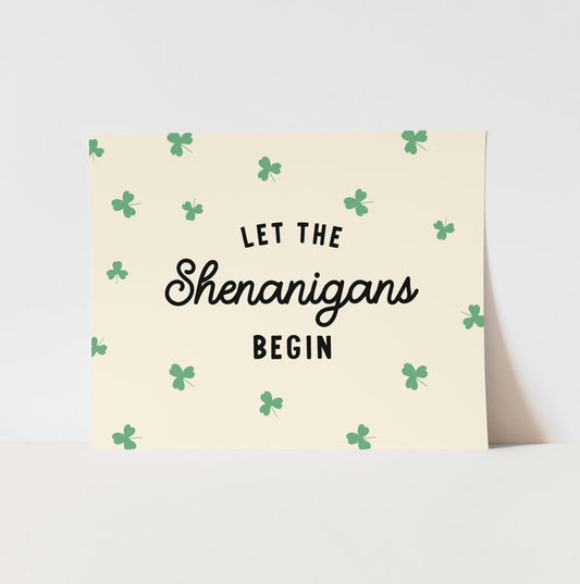 Greeting card with 'Let the Shenanigans Begin' text and shamrock pattern on a light background