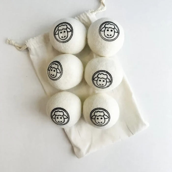 Set of six white laundry detergent pods with black sheep faces in a drawstring bag on a light background