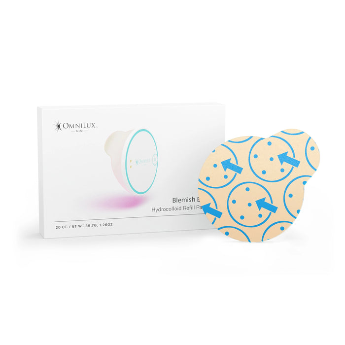 A person with short brown hair and multiple ear piercings uses the OMNILUX round skincare device emitting red light on their forehead, which is covered by an OMNILUX - BLEMISH ERASER HYDROCOLLOID PATCH REFILL KIT patch.