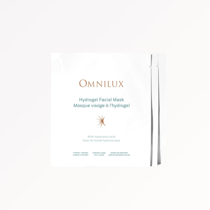 A woman removes an OMNILUX - HYDROGEL FACIAL MASK infused with Hyaluronic Acid from her face. Text above reads, “Includes 3 Hydrogel Facial Masks by OMNILUX.”.