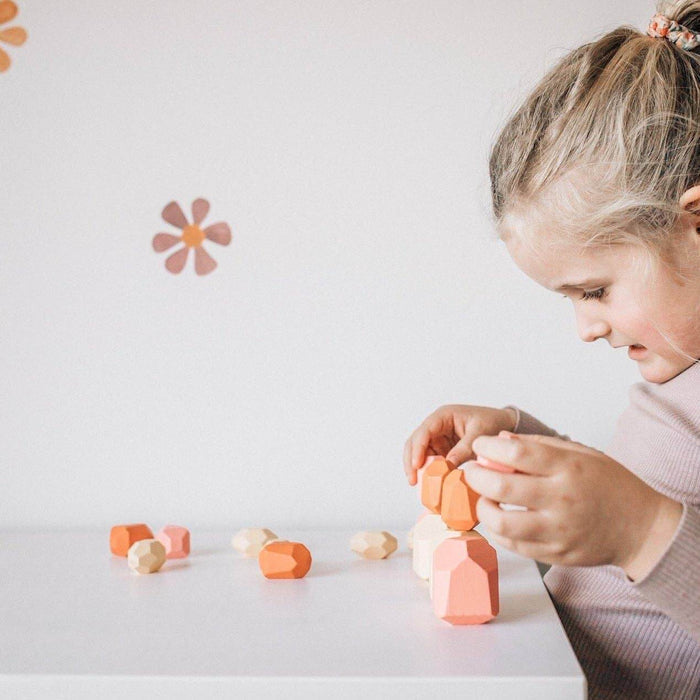 Child playing with colorful wooden blocks on a white surface